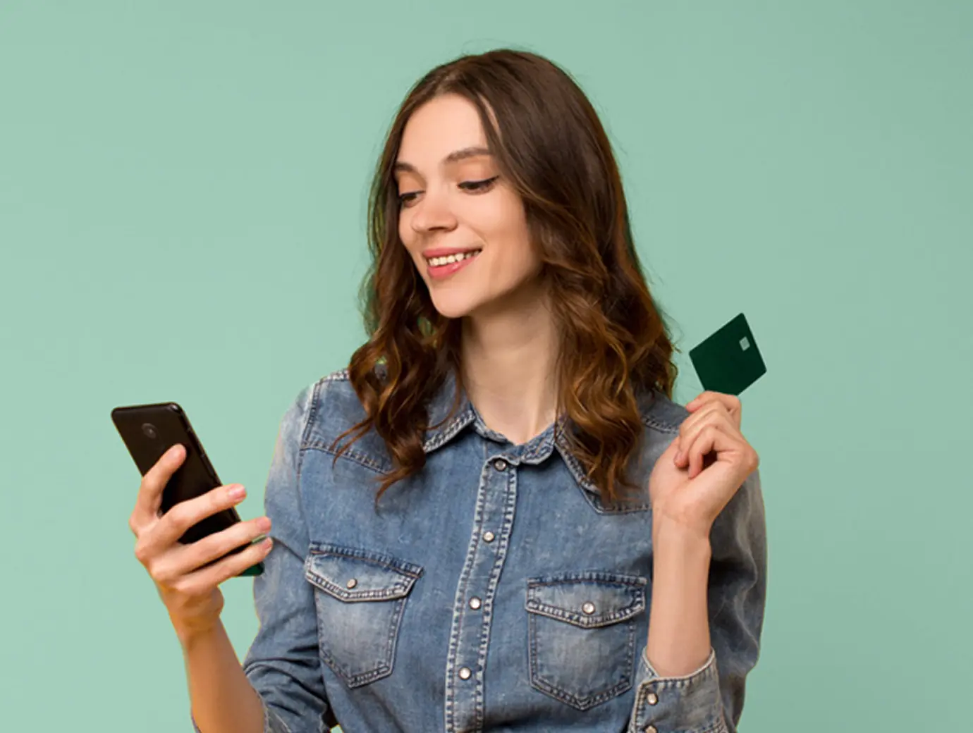 Woman looking at phone and holding credit card